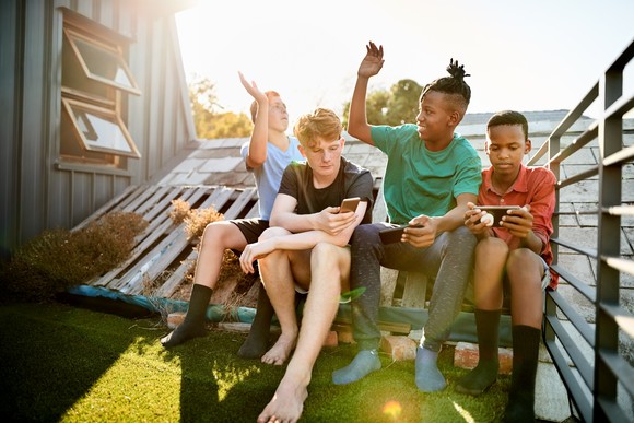 Four teenagers using smartphones to play games.