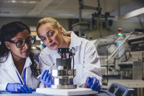 Two scientists examining a piece of lab equipment. 
