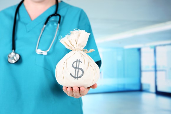 Healthcare professional holding a money bag.