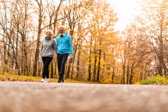 Two older people walking in a park.
