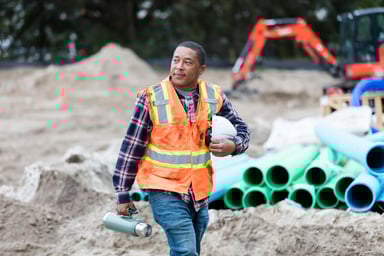 a construction worker holds a thermos and helmet