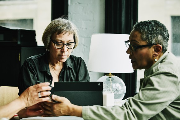 Two people in an office talking and looking at a computer.