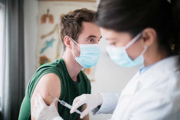 A healthcare professional giving a shot in the arm of a patient.