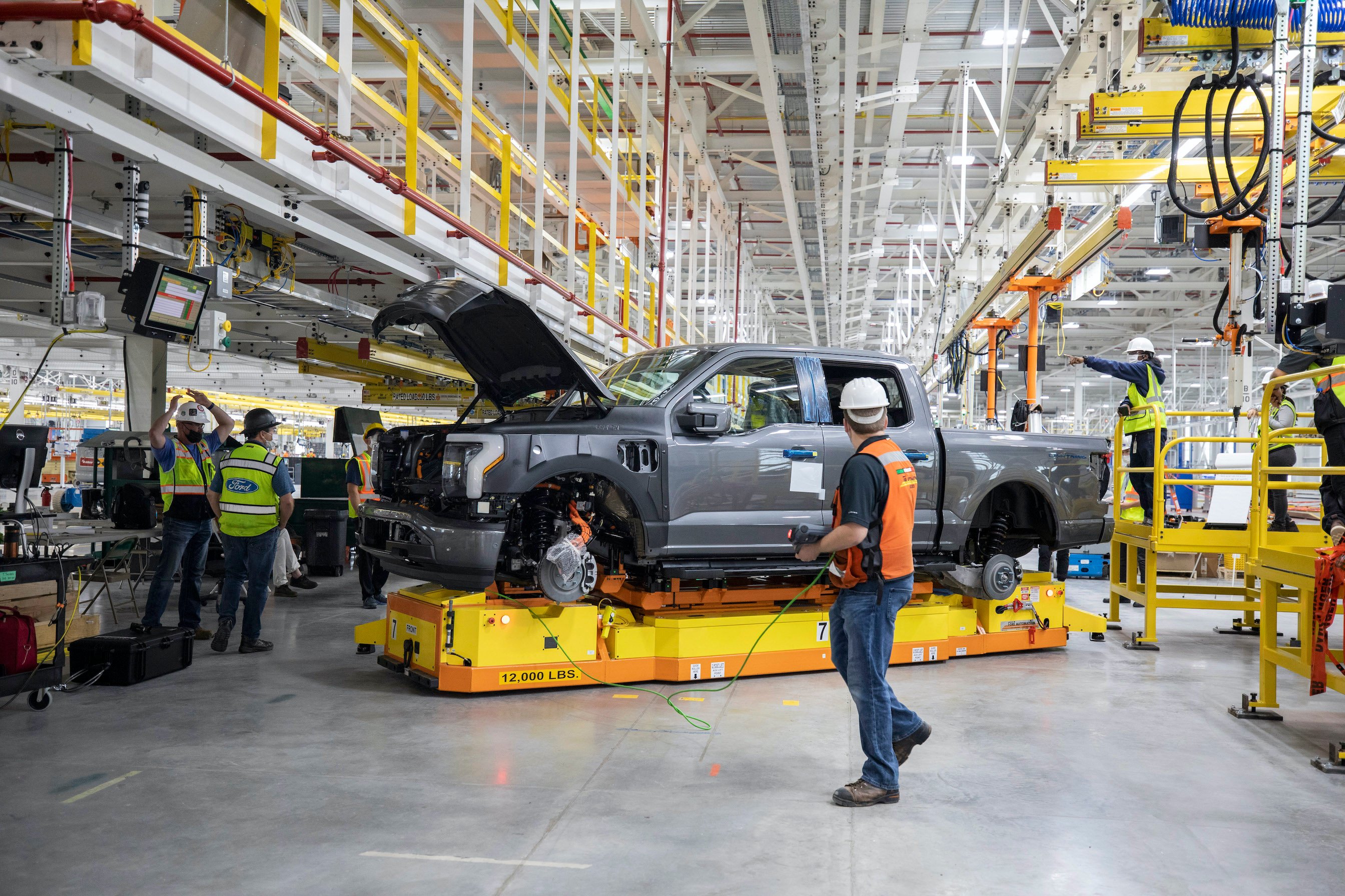 Workers tend to a partially-assembled F-150 Lightning electric pickup at a Ford factory in Dearborn, Michigan.