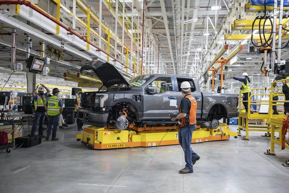Workers tend to a partially-assembled F-150 Lightning electric pickup at a Ford factory in Dearborn, Michigan.