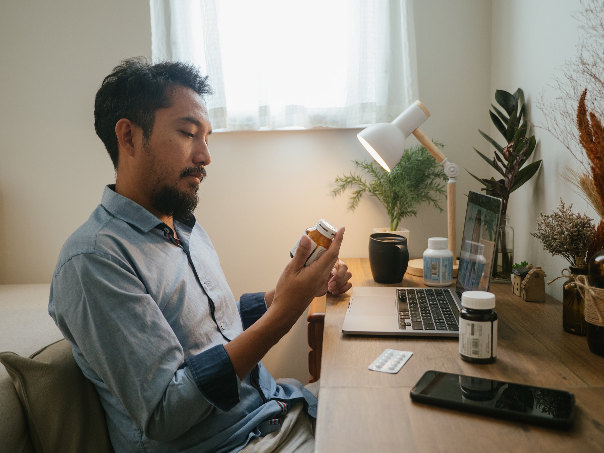 A person sitting at a desk looking at a medicine vial.