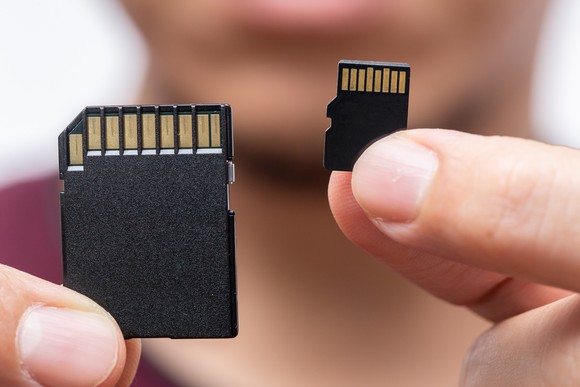 Closeup of two memory chips held by a person comparing their sizes. 