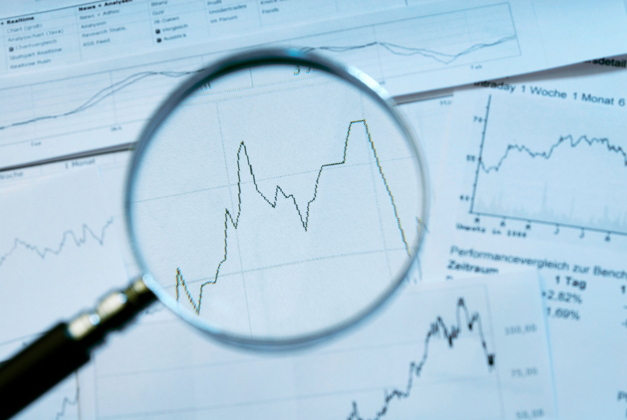Magnifying glass looking at chart with volatility.