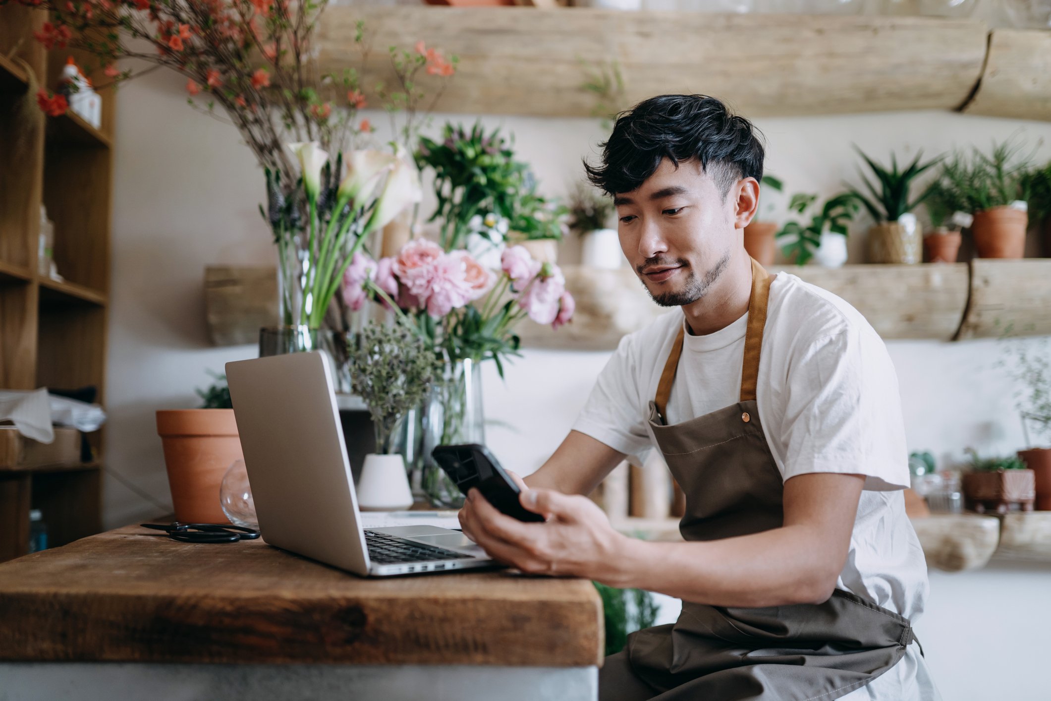 A person uses a smartphone in a flower shop.