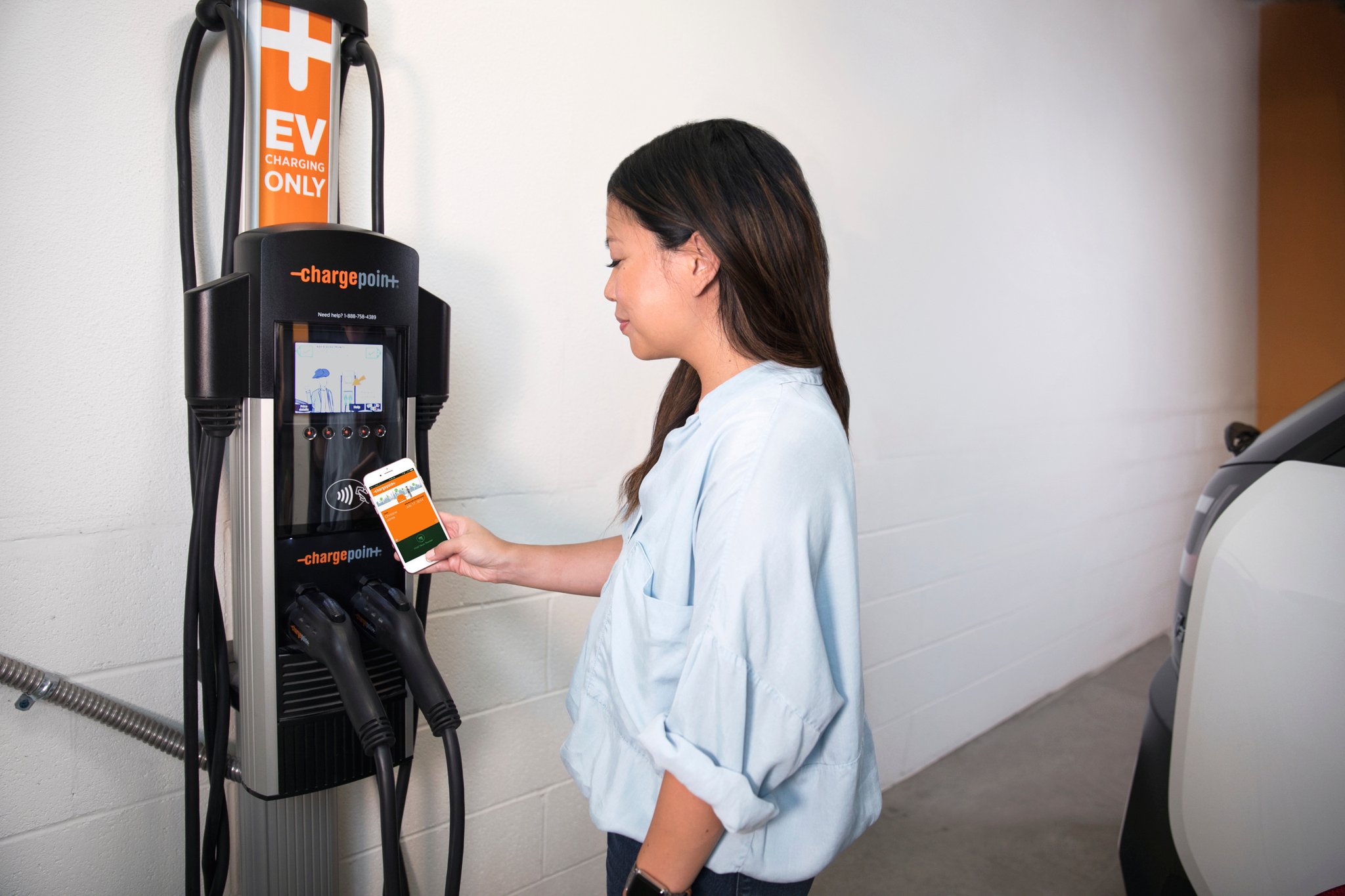 EV driving using ChargePoint app at charger in parking space.