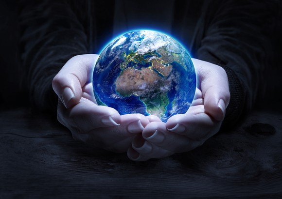 A pair of hands cupped together holding the planet Earth.