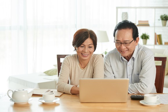 Two smiling people looking at a laptop.
