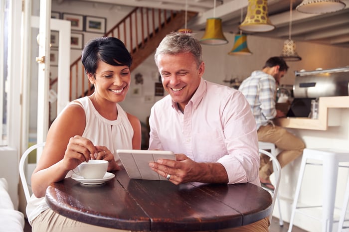 Two smiling people looking at a digital tablet.