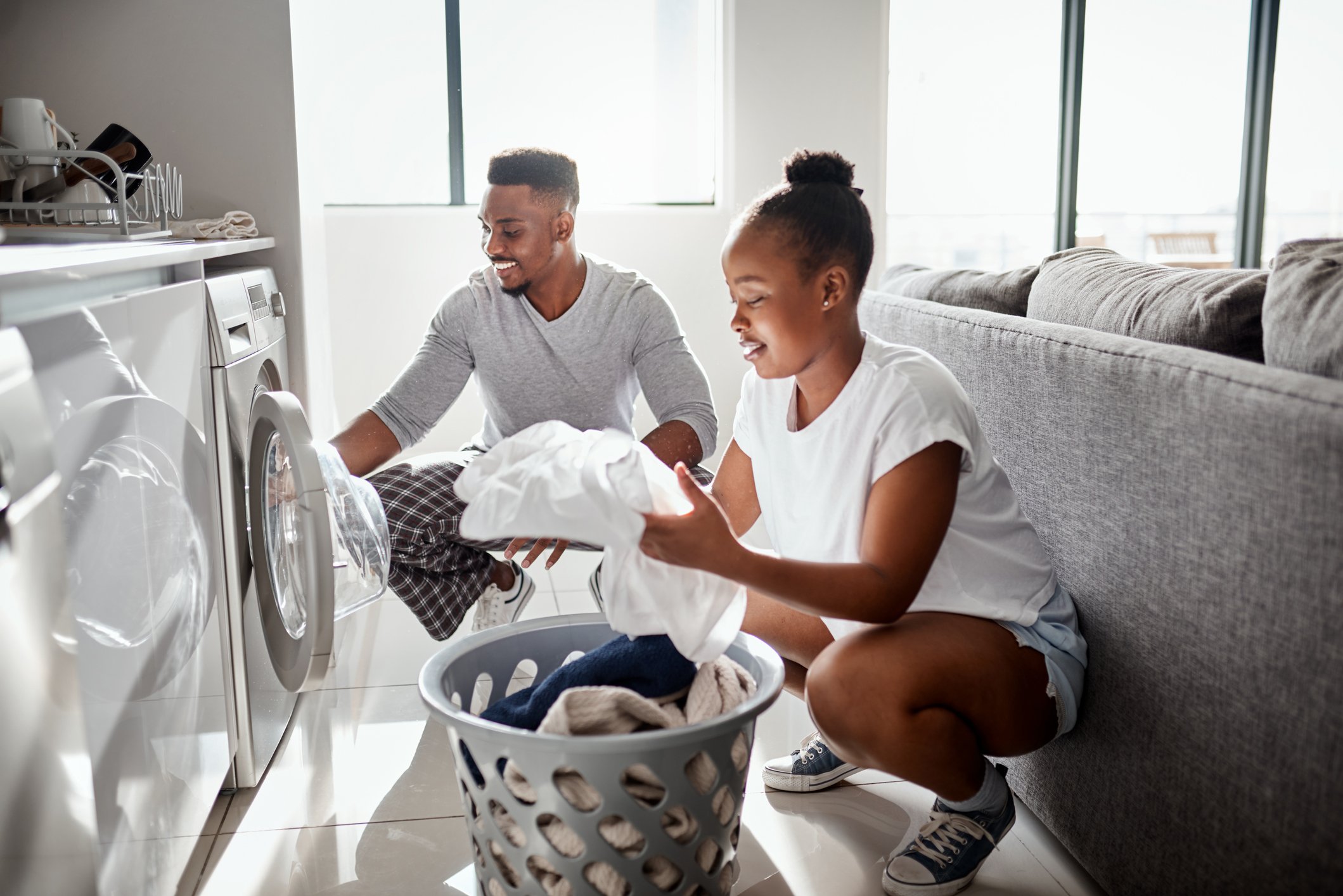Two people taking laundry out of the dryer at home. 
