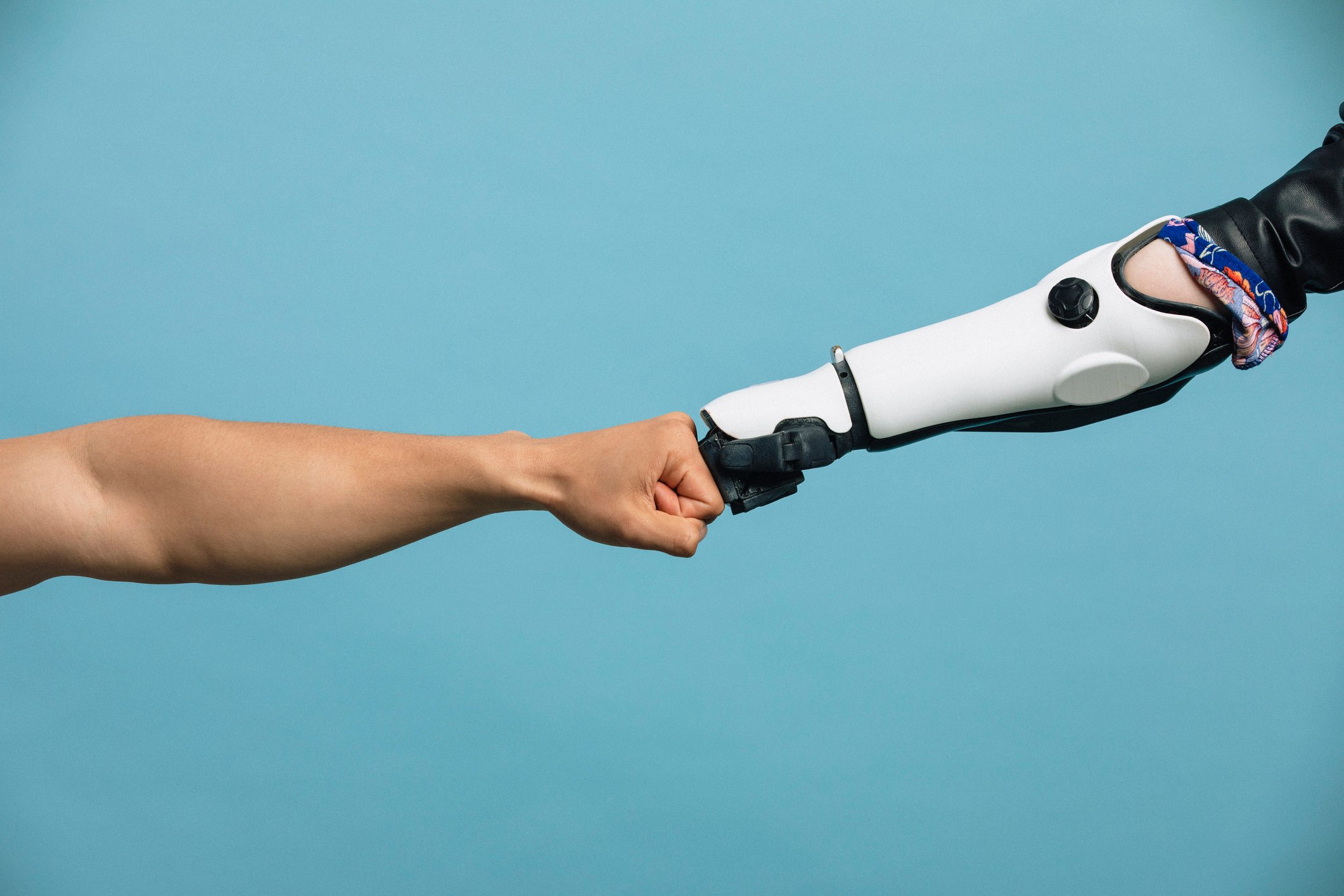Human hand fist-bumping a robot hand.