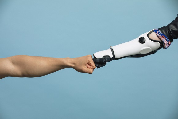 Human hand fist-bumping a robot hand.