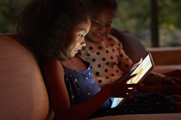 Two children looking at a tablet with a video game on it.