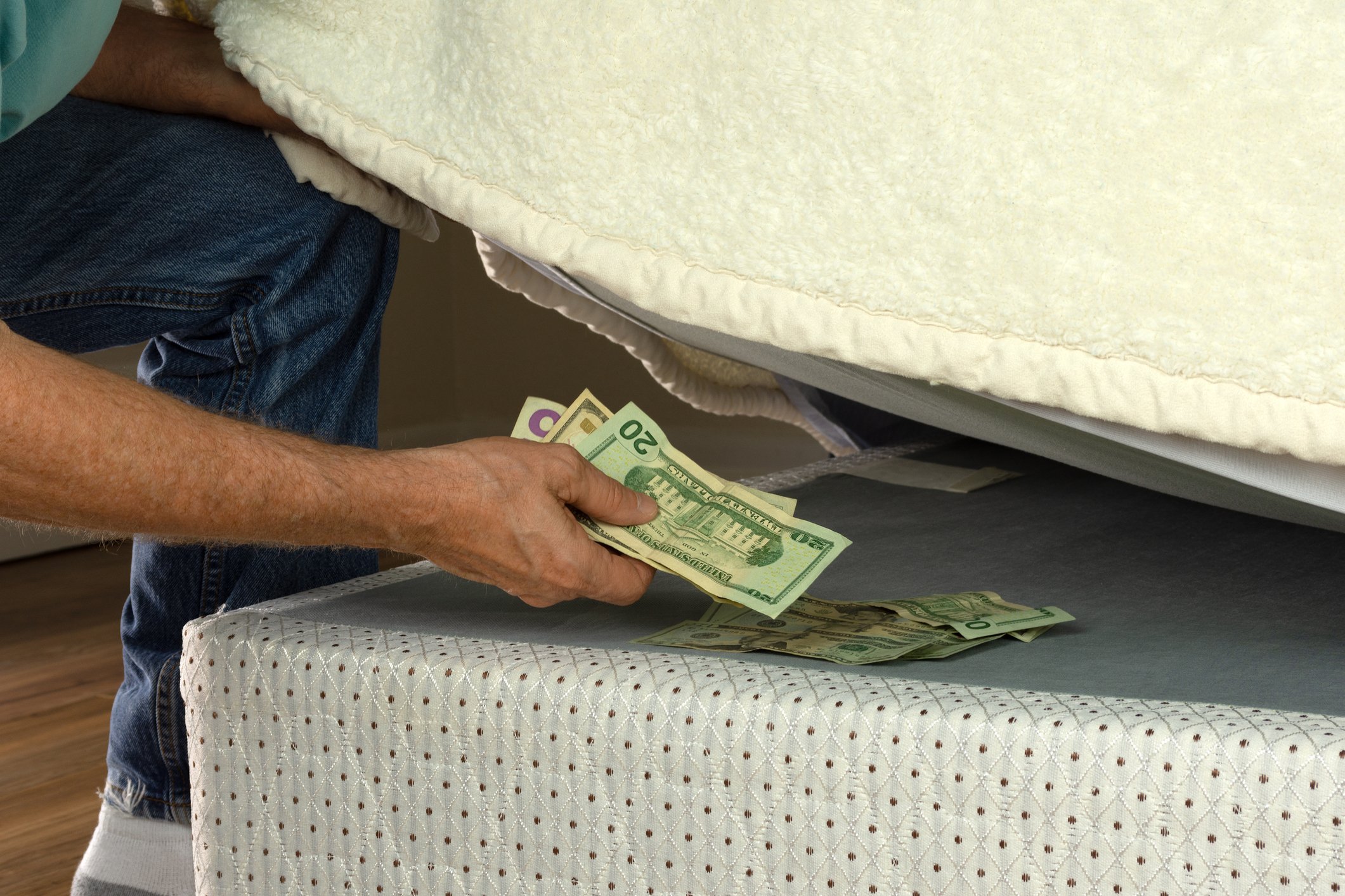 A person placing cash under a mattress.