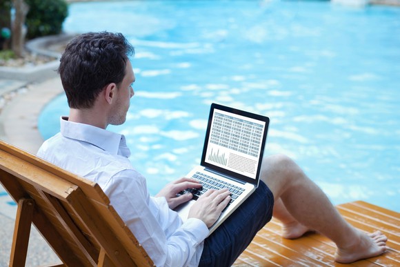 investor on laptop relaxed by the pool.