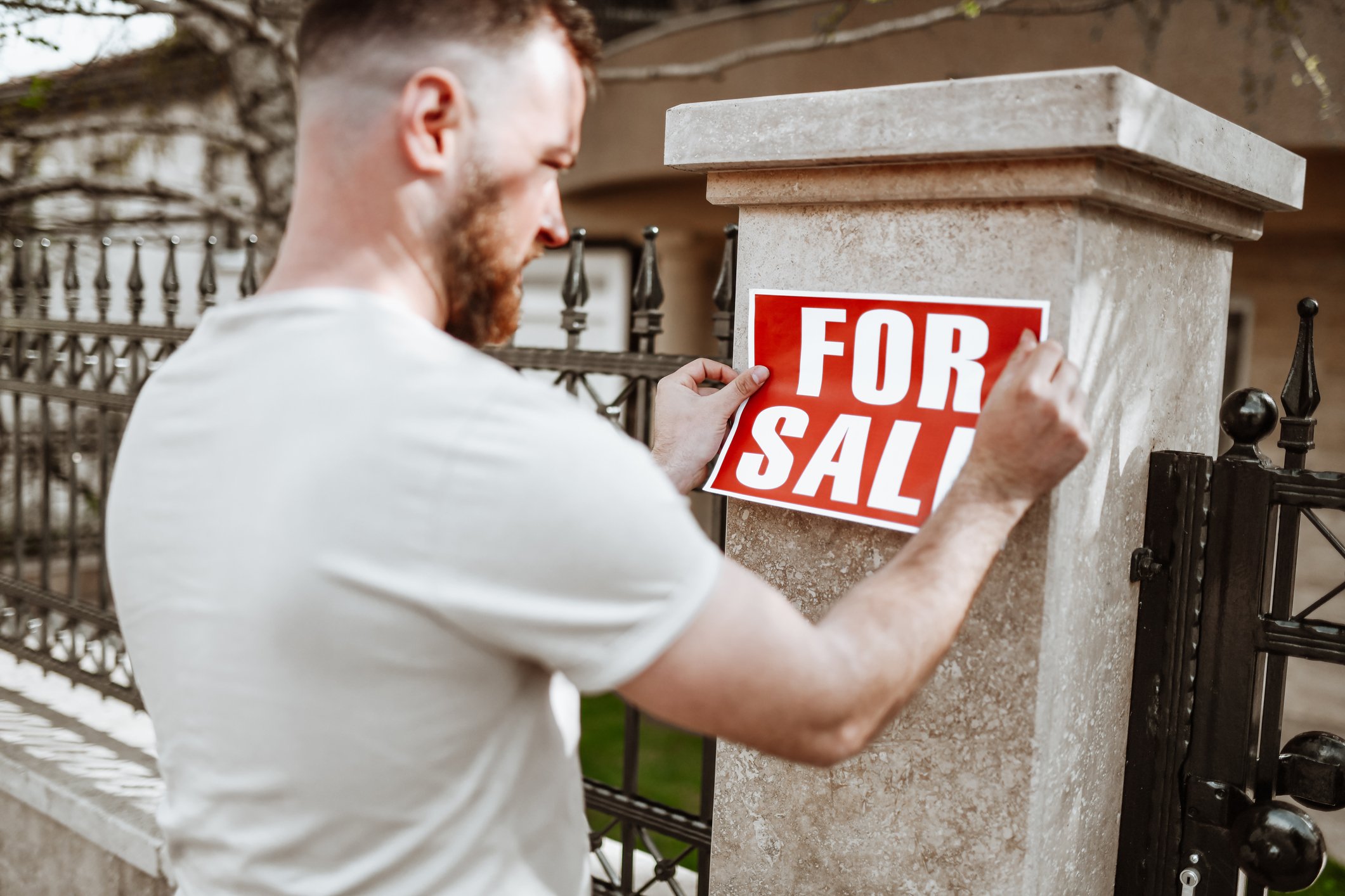 Person putting for sale sign on house.