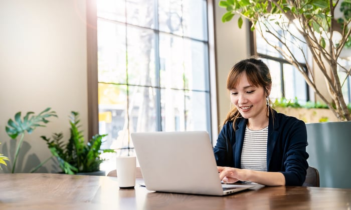 A person using a laptop in bright sunny office.