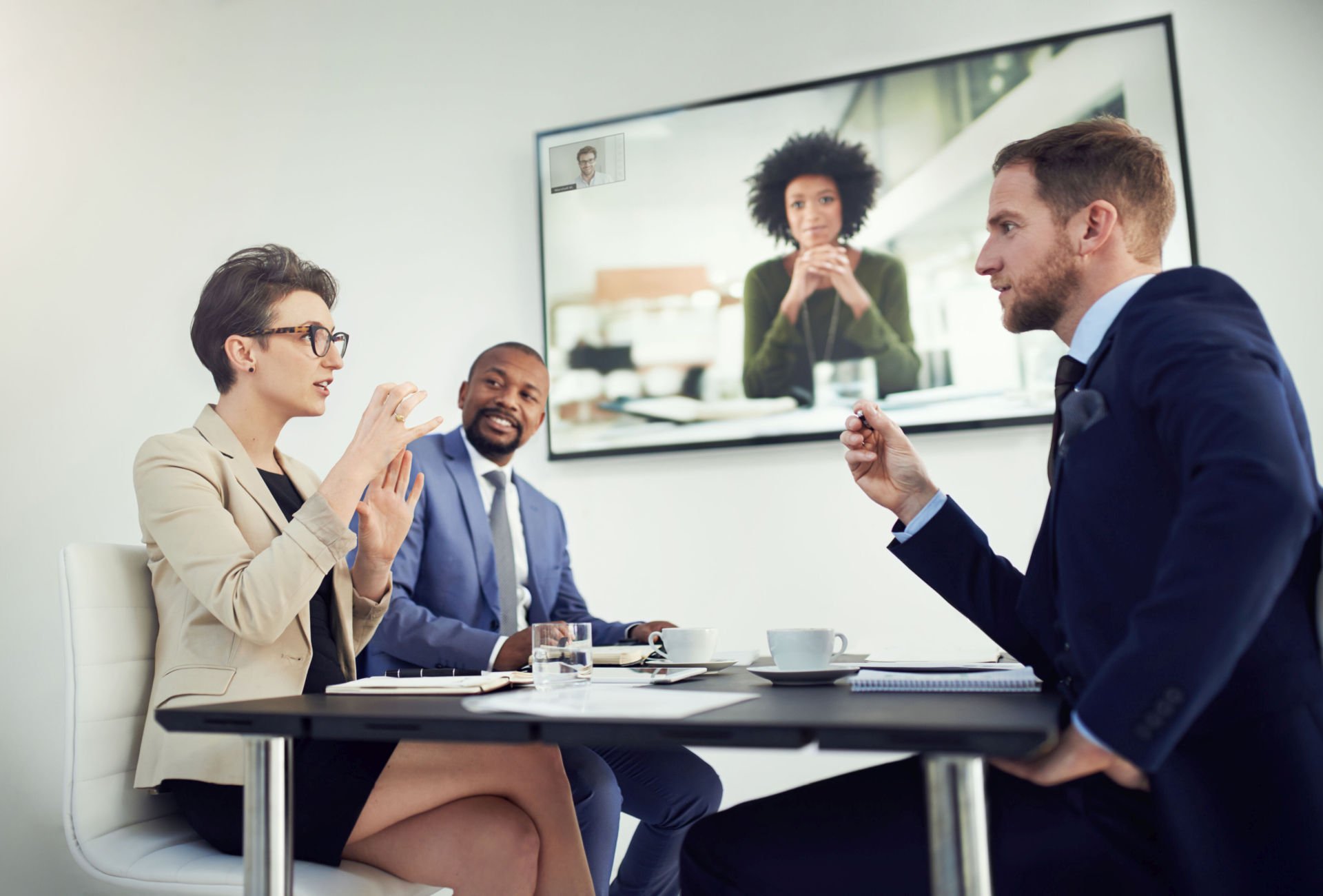 Three workers attend a Zoom call with a remote worker.