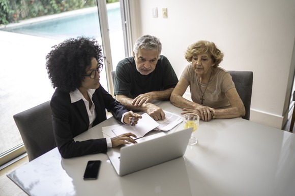 Person helping two individuals look over documents.