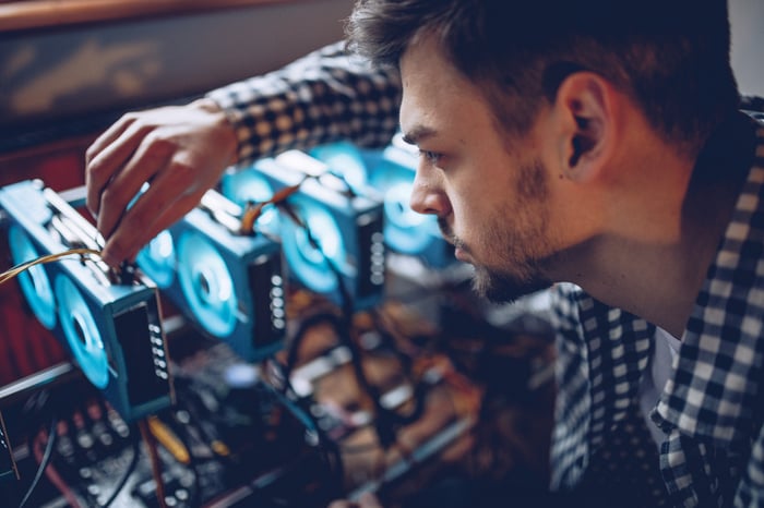 A man hooking up a Bitcoin mining device.