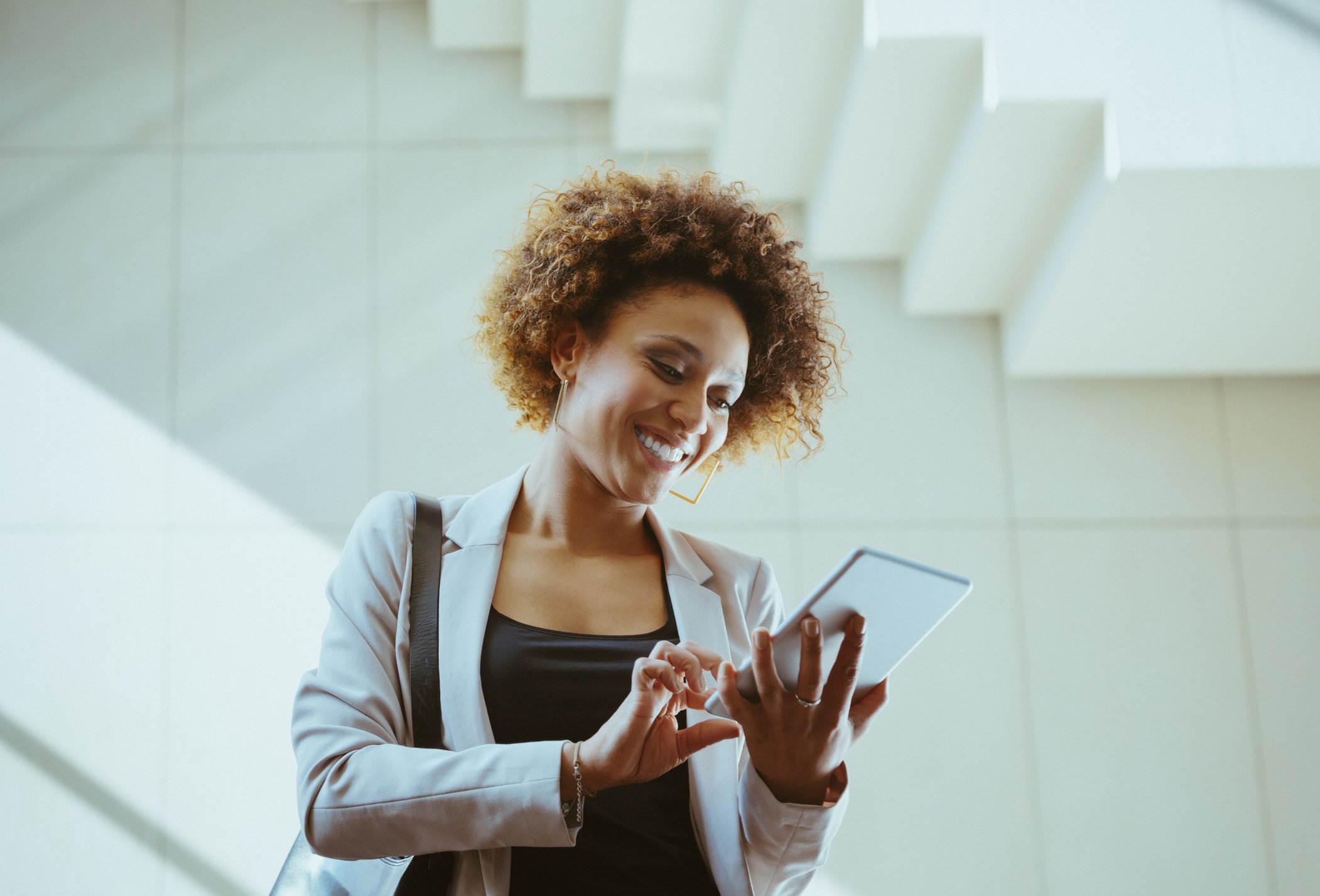An investor smiles while looking at something on a tablet in an office building.
