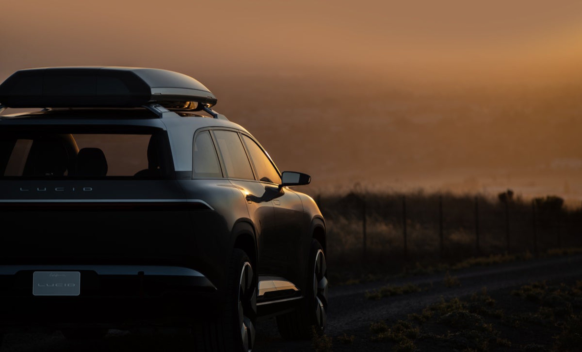 A Lucid Gravity SUV concept car parked overlooking a tree line. 