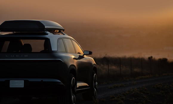 A Lucid Gravity SUV concept car parked overlooking a tree line. 