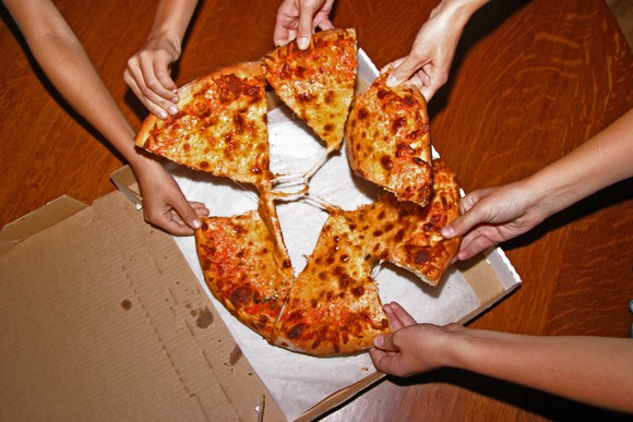 People pulling apart pizza slices.