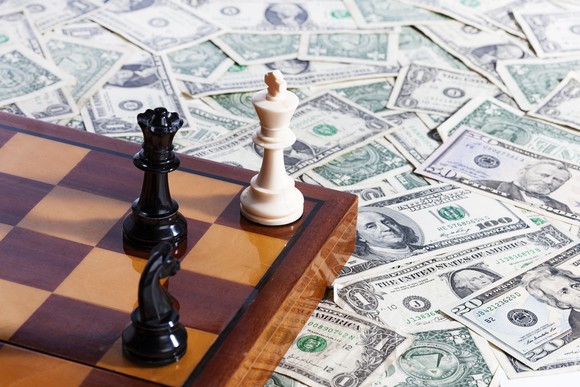 A chess board sitting on a pile of cash.