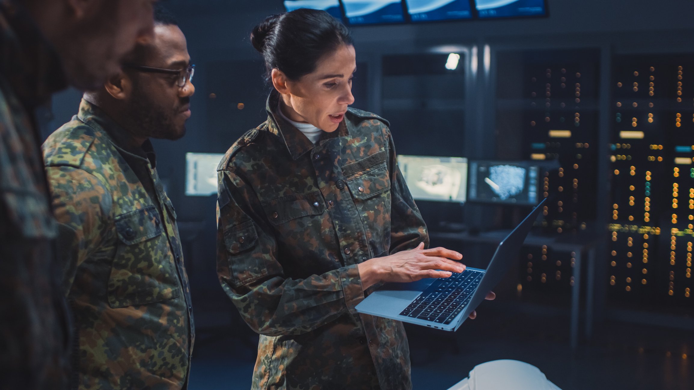 Two soldiers standing and using a laptop.