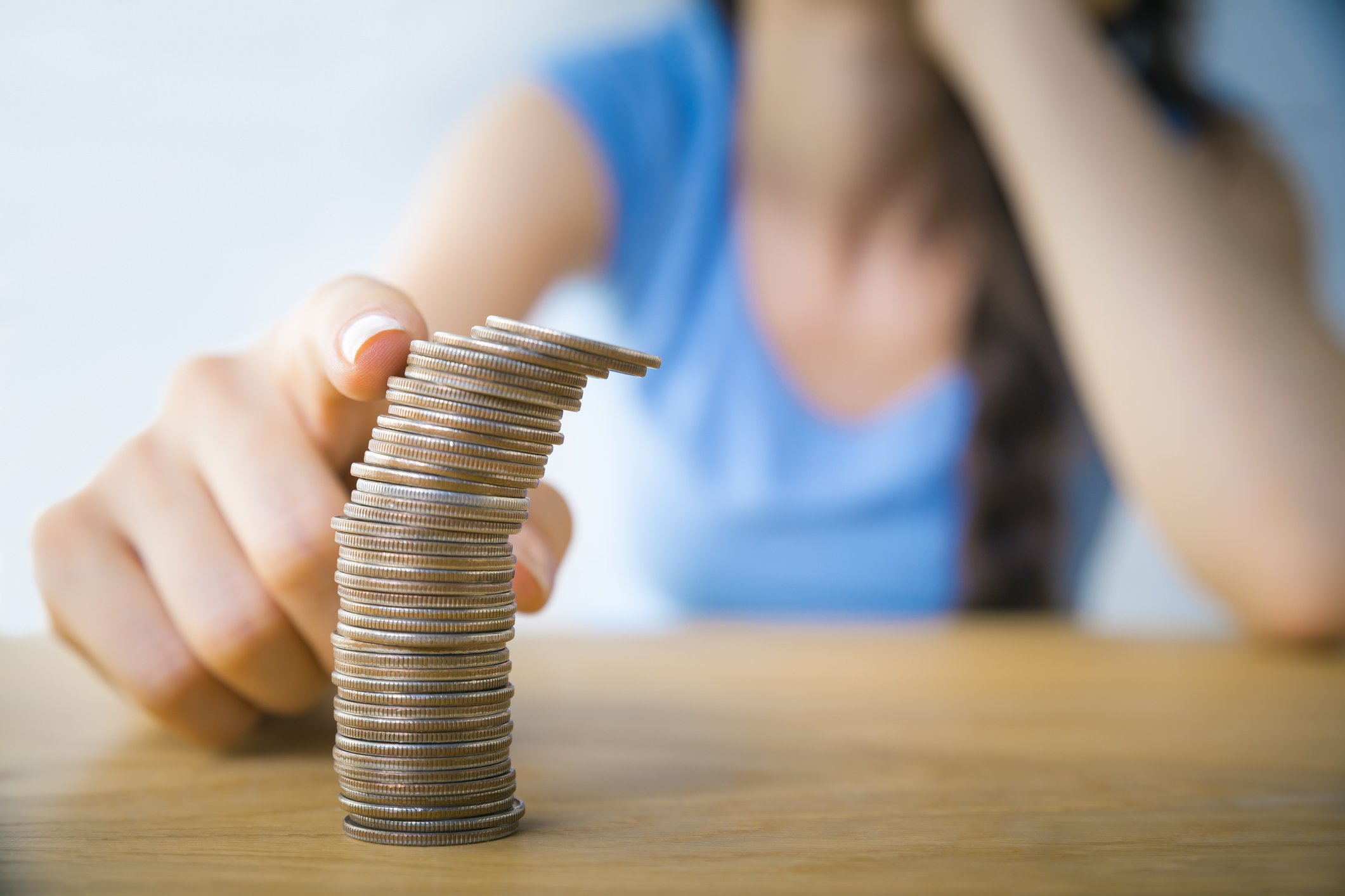 Close-up of a person's finger about to topple a stack of quarters.