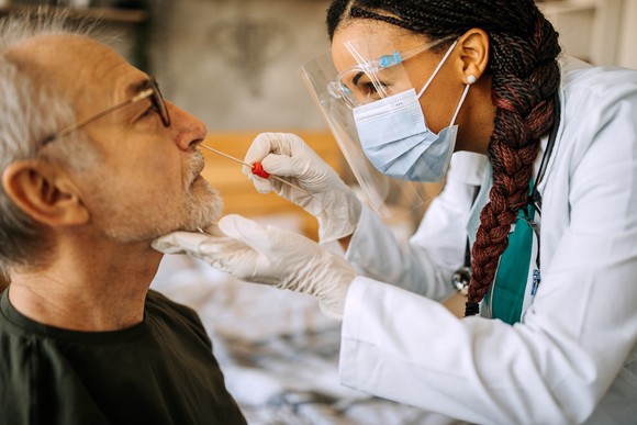 A healthcare worker administers a coronavirus test swab to a patient at a clinic.