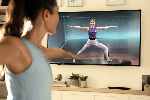 A Peloton user following a workout through the Peloton app on a TV at home.