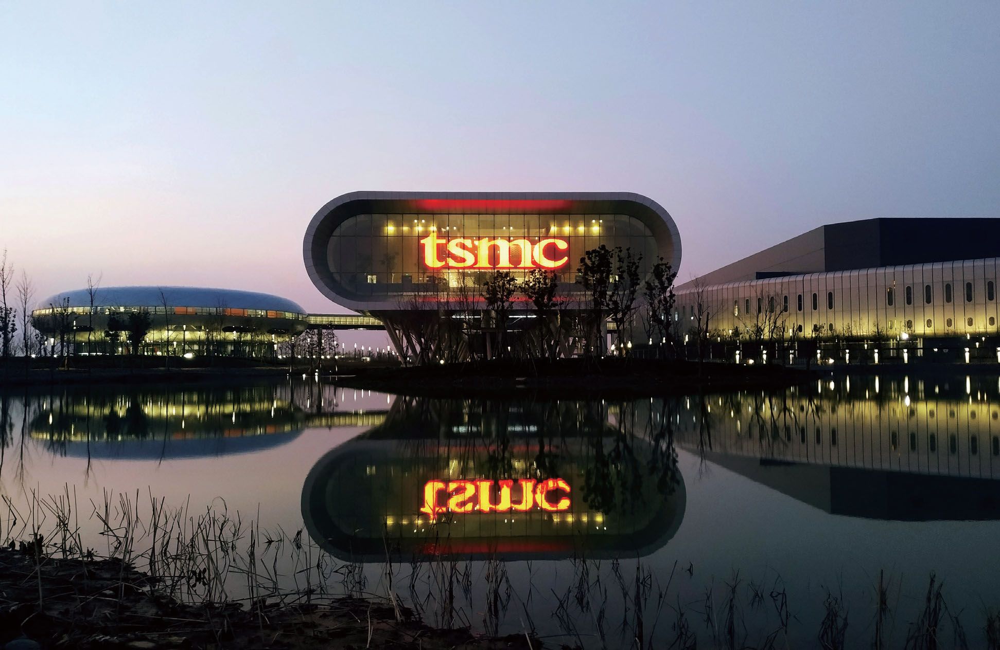 A lighted "TSMC" sign is visible in the factory's window.