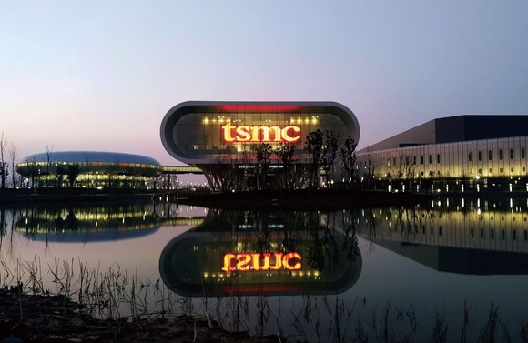 A lighted "TSMC" sign is visible in the factory's window.