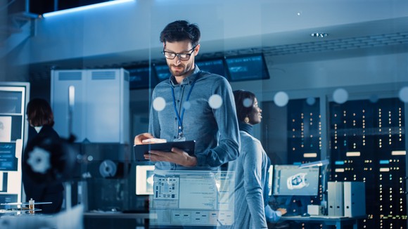 An IT worker looks at his tablet in a server room. 