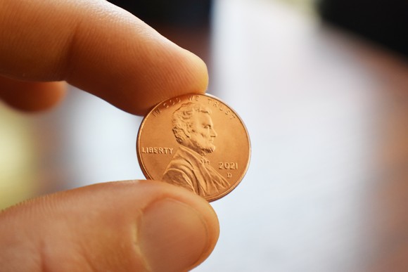 Fingers holding a penny.