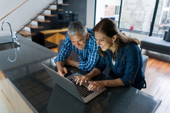 Two smiling people looking at a laptop.