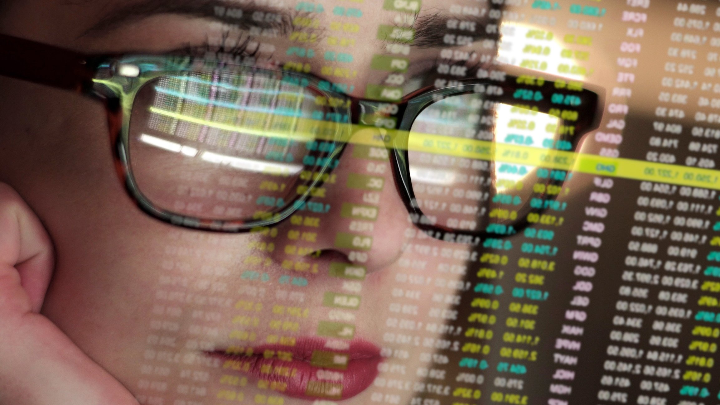 Woman with stock prices reflecting in her glasses