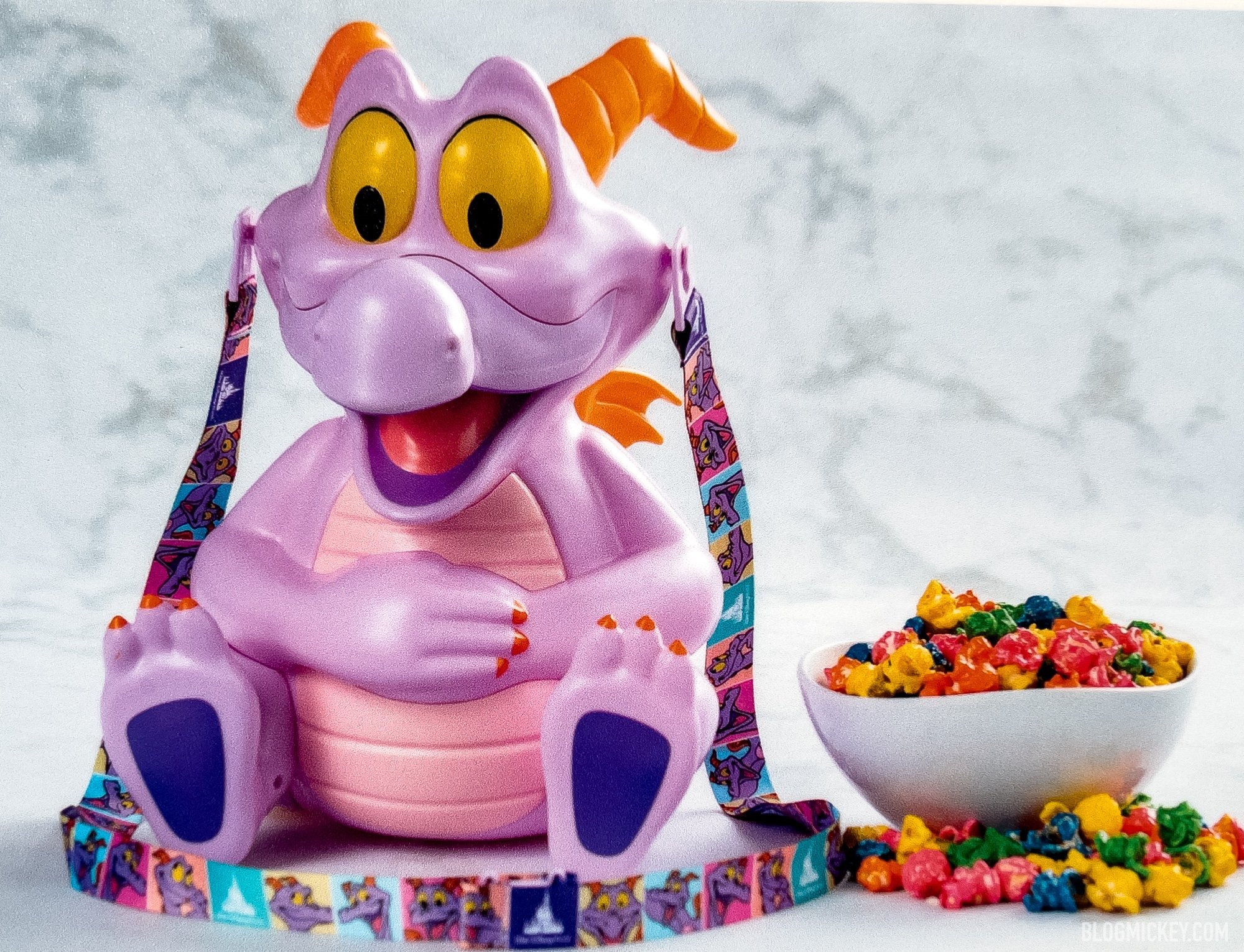 A Figment popcorn bucket with rainbow colored popcorn in an adjacent bowl.
