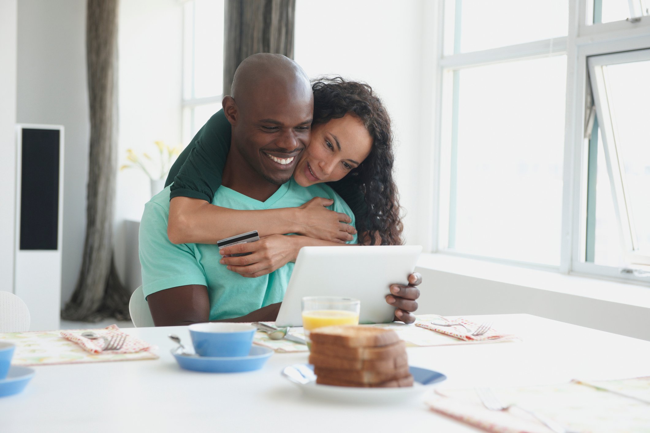 A couple looking at a tablet during breakfast.