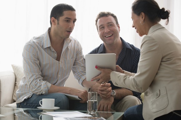 One person showing two other people something on a tablet.