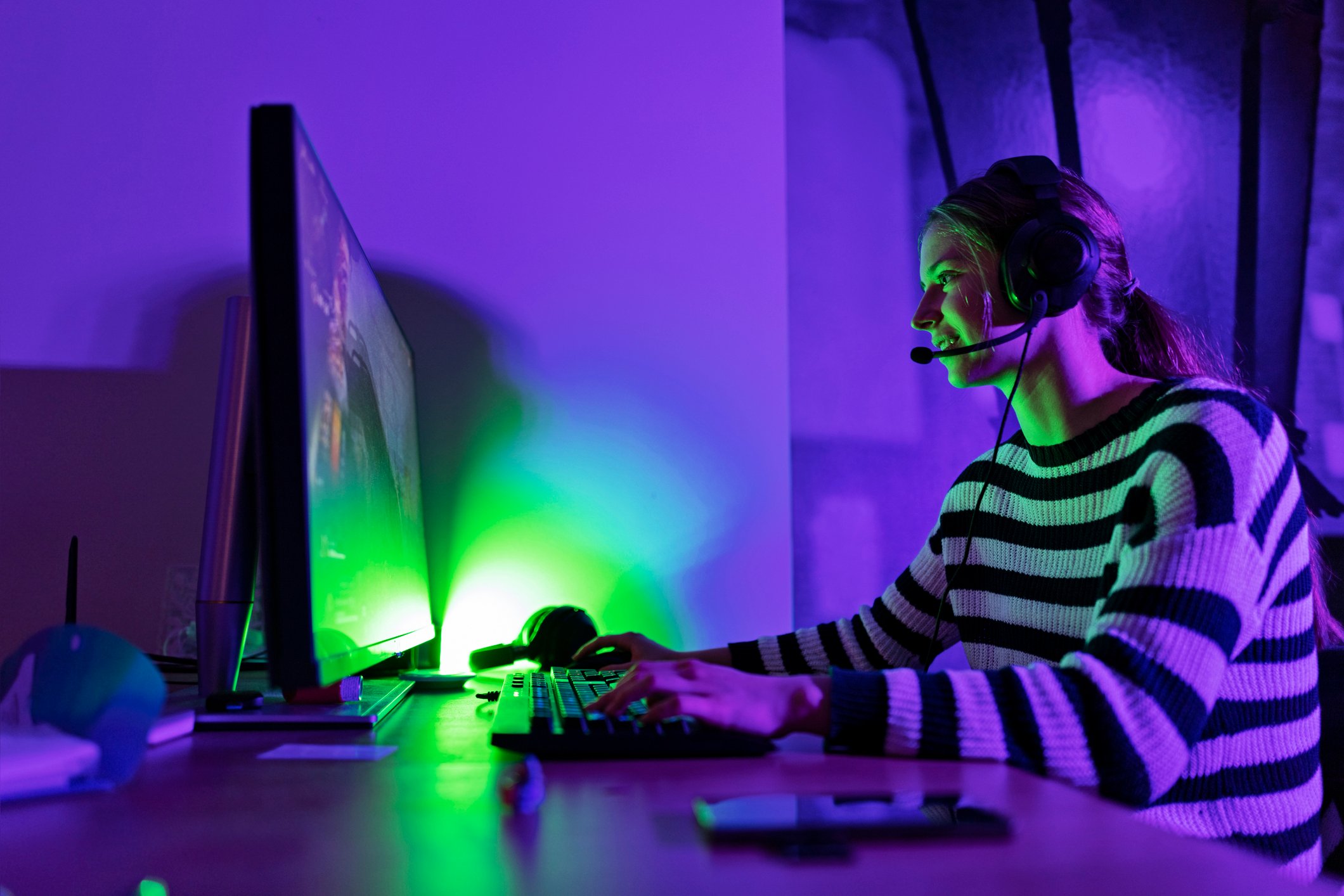 A person playing video games on a computer while wearing a headset.