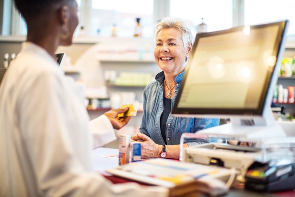 A pharmacist returns a credit card to a client after receiving payment. 