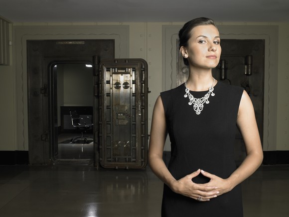 Person with hands crossed in front of a bank vault.