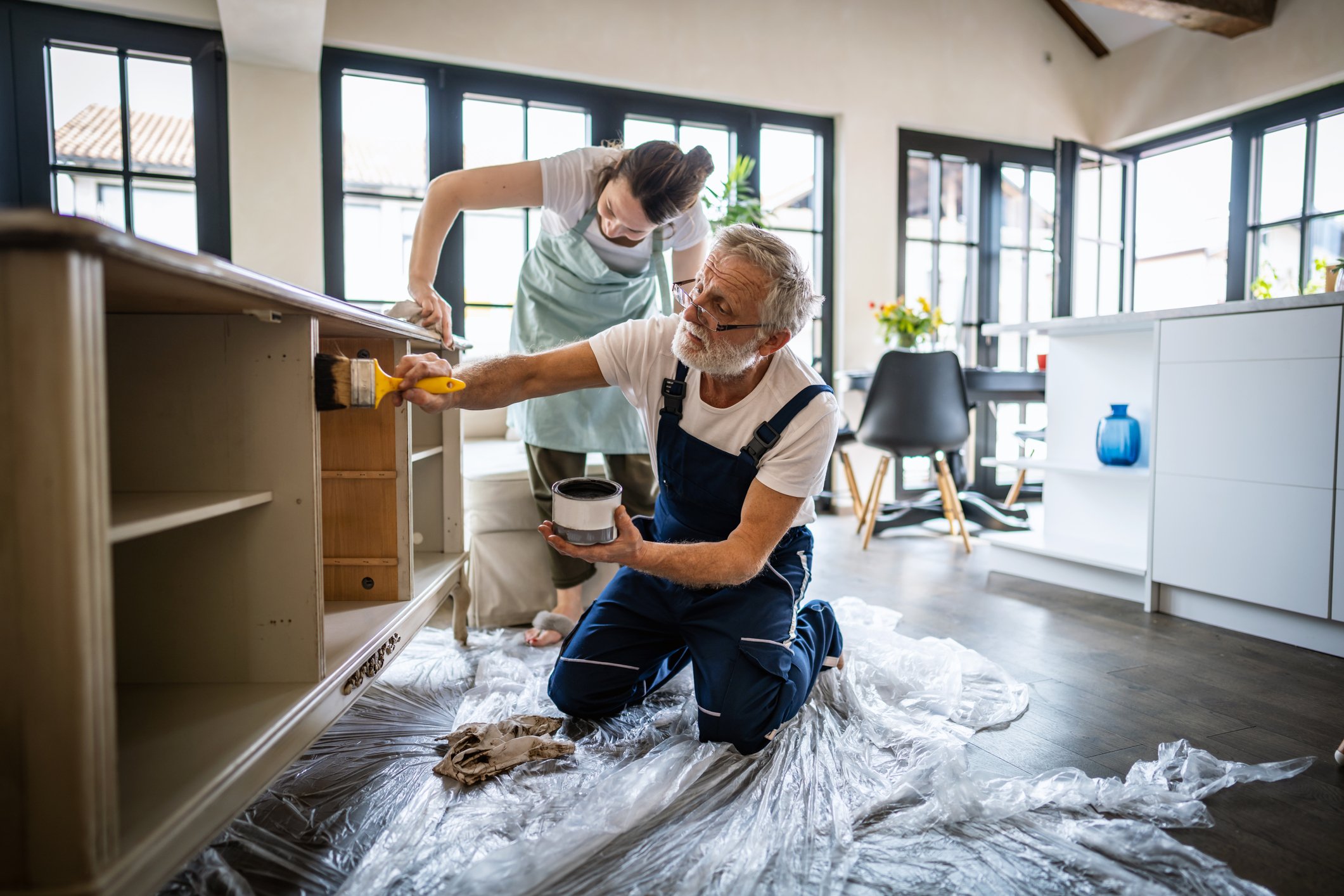 Older person and young person painting cabinets.